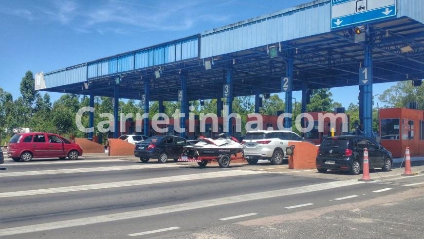 Automóvel rebocando uma carretinha em rodovia com praça de pedágio