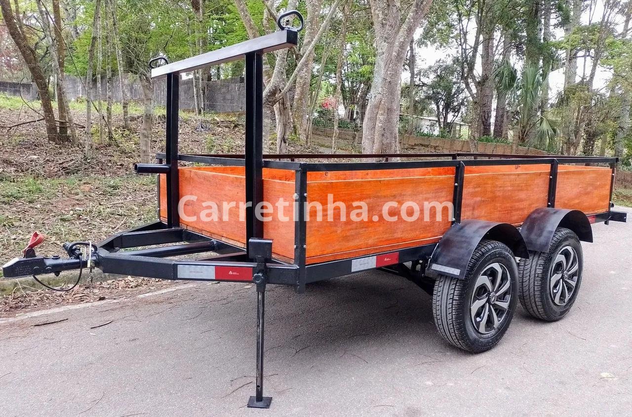Carretinha fazendinha de dois eixos com estrutura metálica e laterais de madeira.
