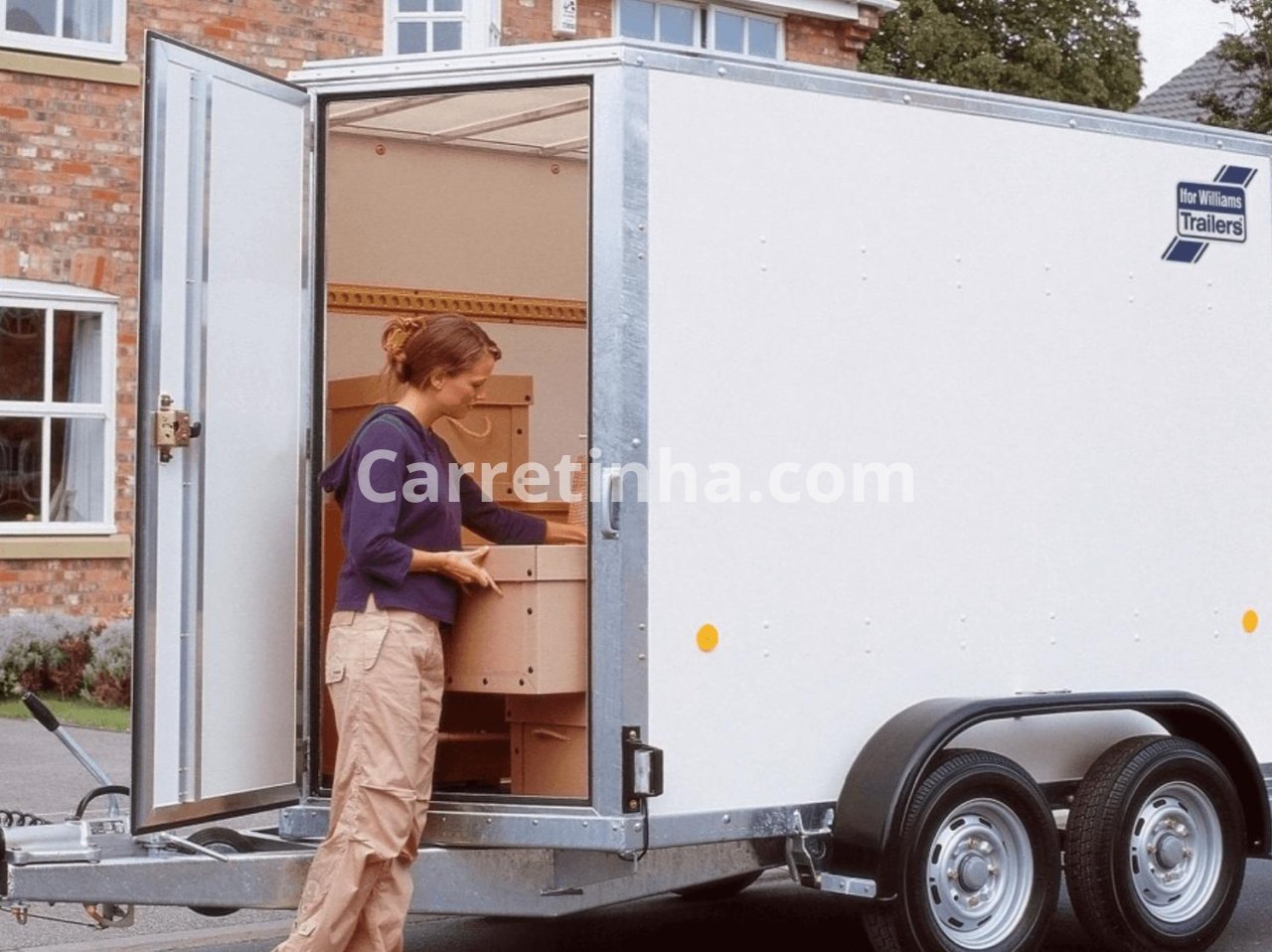 Compartimento de carga de um reboque comercial com porta lateral aberta, permitindo retirar encomendas menores sem precisar acessar toda a carga pela traseira.