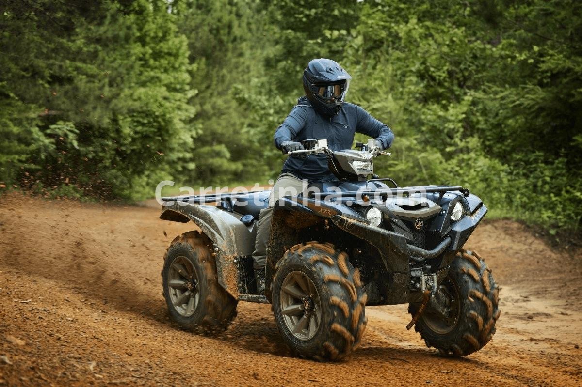 Quadriciclo de perfil utilitário e aventureiro em uma trilha de floresta, representando a categoria de ATVs robustos para terrenos variados.