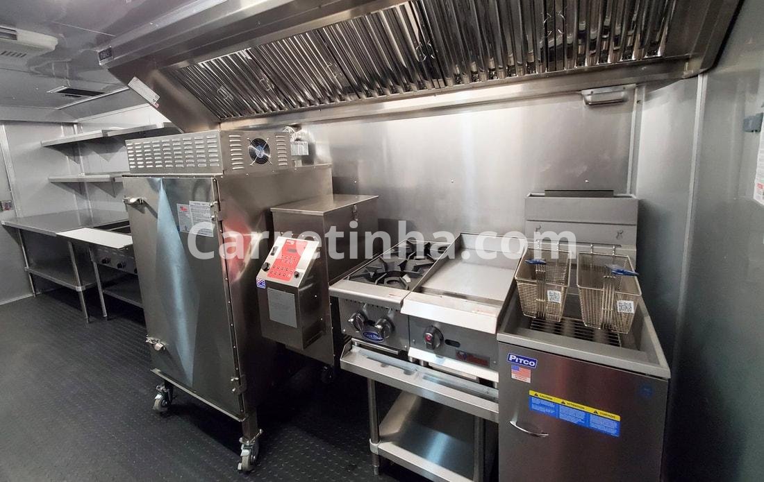Chapa, fritadeira, refrigeração e sistema de exaustão em uma cozinha compacta, representando equipamentos comuns em operações de lanches.