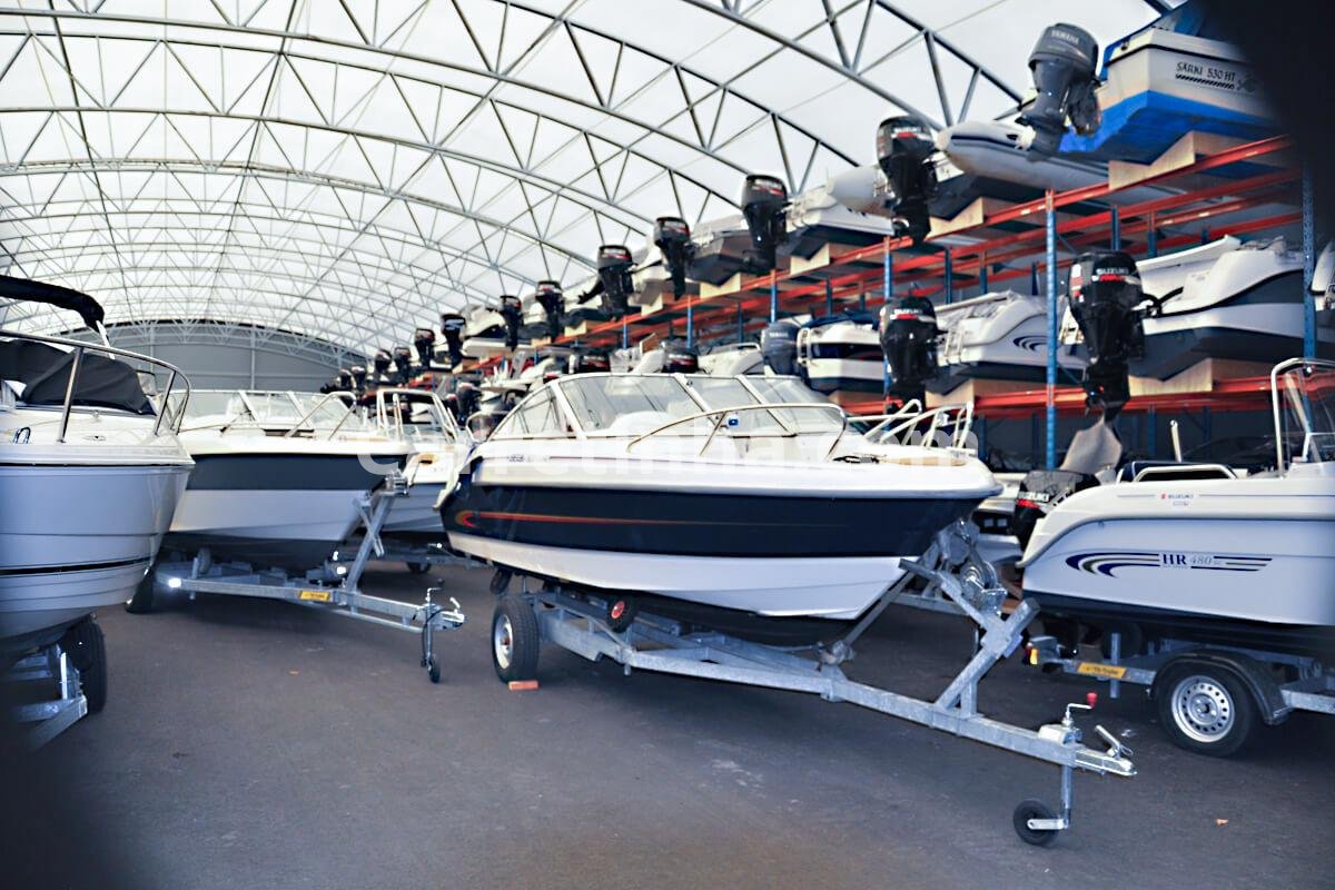 Embarcação armazenada fora da água, apoiada em estrutura apropriada dentro de um galpão de garagem náutica.