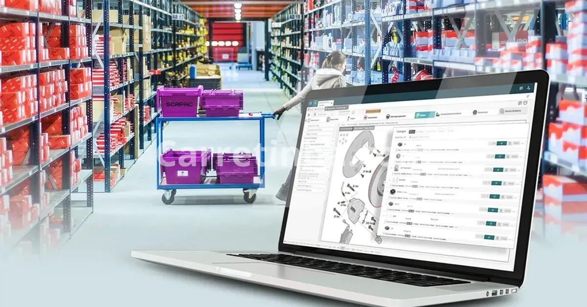 Profissional de uma distribuidora organizando o catálogo de produtos em um computador, com peças de reposição armazenadas ao fundo.