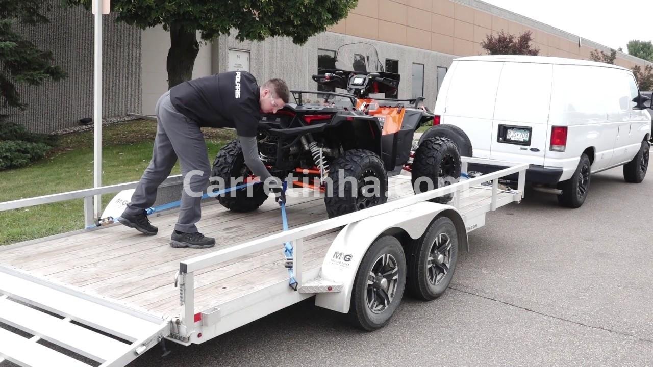 Quadriciclo preso a um reboque com cintas de fixação, demonstrando a importância de avaliar separadamente a proteção do equipamento e do veículo de transporte.