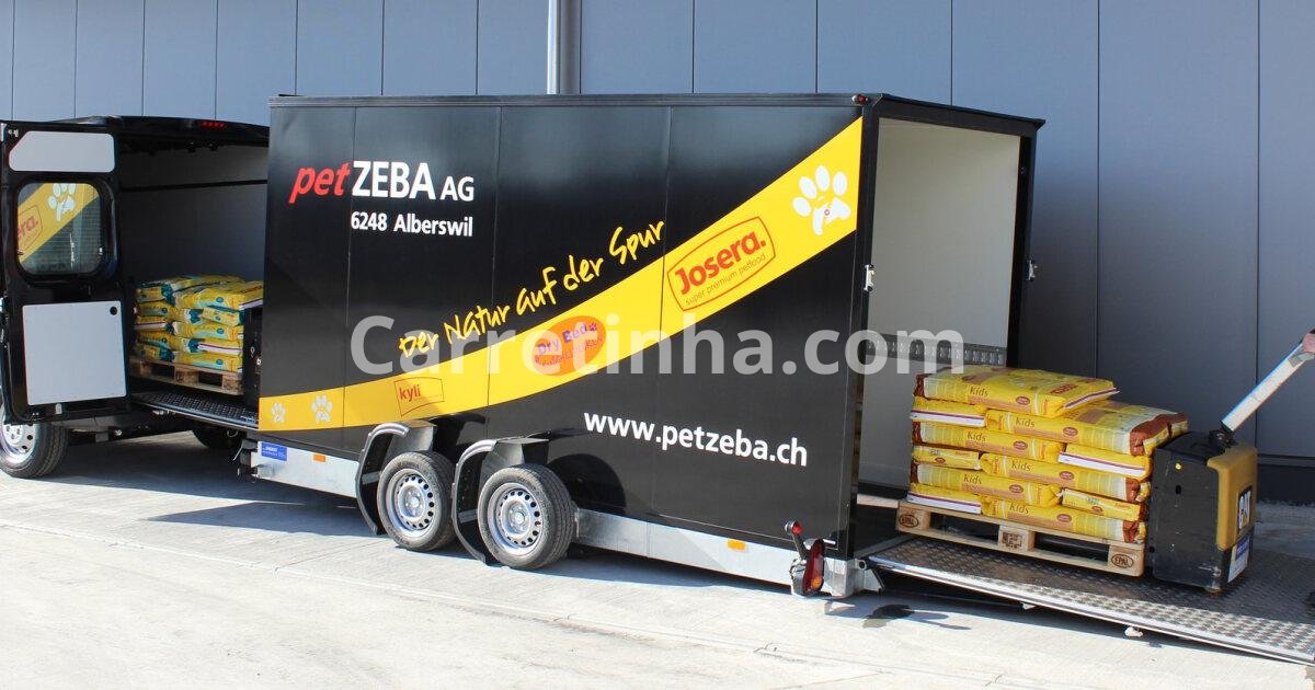 Reboque leve transportando sacos de ração e produtos para animais em frente a um estabelecimento comercial.